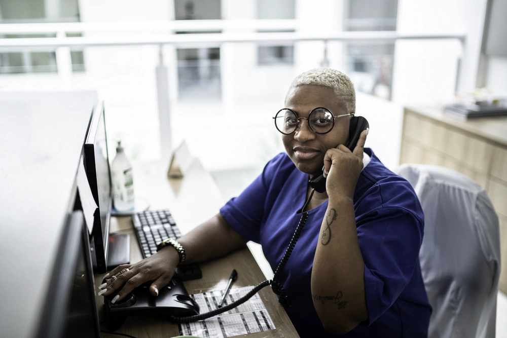 medical assistant answering phone while typing on computer