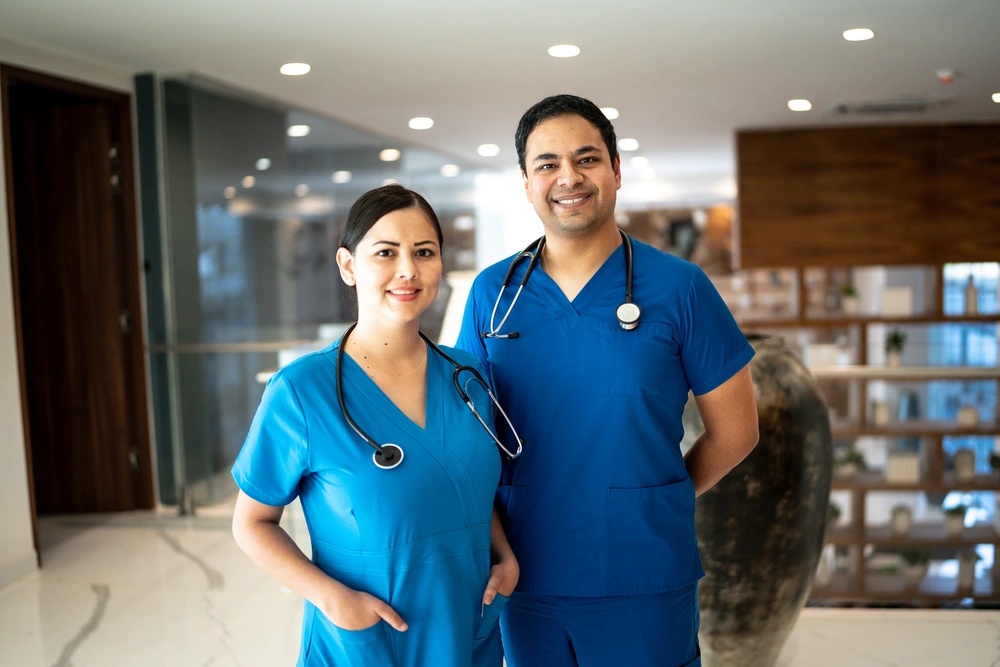 Smiling female and male medical assistant standing next to each other in waiting room